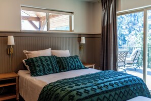Une chambre à coucher avec un lit, deux lampes de chevet, une fenêtre et un balcon équipé d’une table et de chaises.