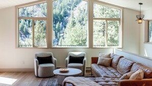A spacious living room with a large window, a brown leather sofa, two armchairs, and a coffee table. - Breathtaking View 12 Min to Downtown (Durango)