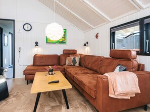 En stue med en brun lædersofa, et træbord og en stor hvid lysekrone.