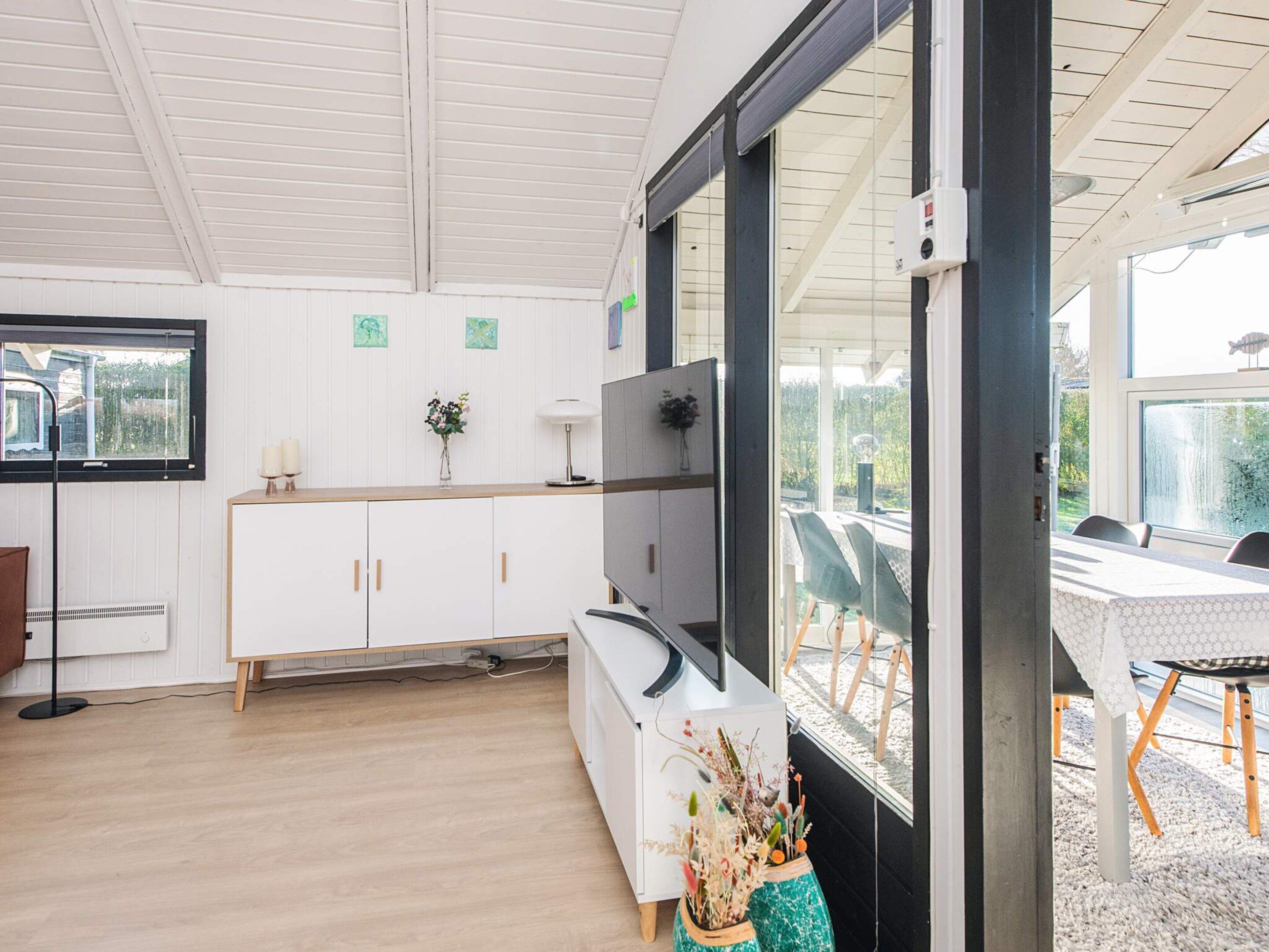A modern kitchen with white cabinets, a built-in oven, and a large window overlooking a garden.