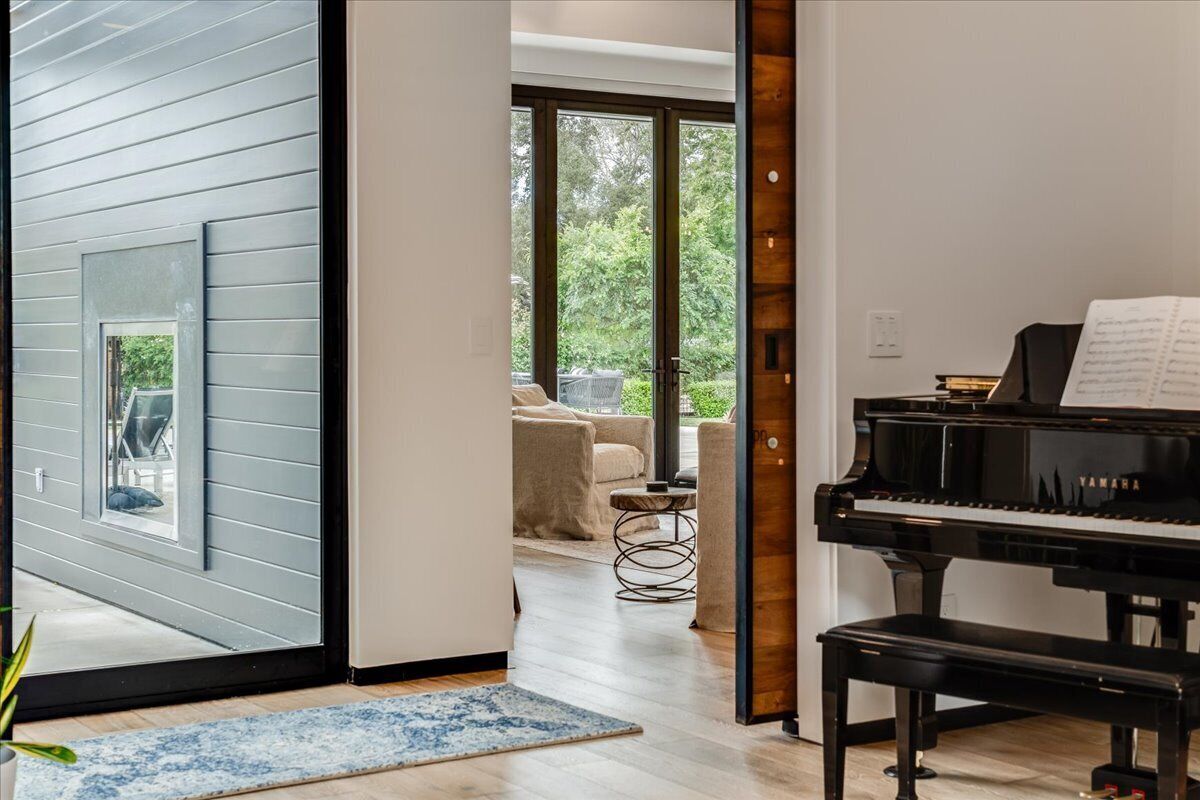 Un intérieur moderne avec un piano à queue, une grande fenêtre et une vue sur l’extérieur.
