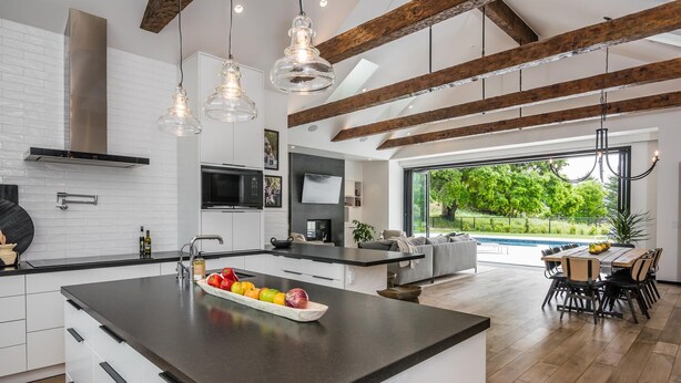 A modern kitchen with a central island, built-in appliances, and a dining area with a view of a swimming pool.
