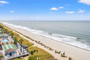 A beach resort with a swimming pool, lounge areas, and a view of the ocean. - Beachfront Condo with Ocean Balcony and Pools (Myrtle Beach)