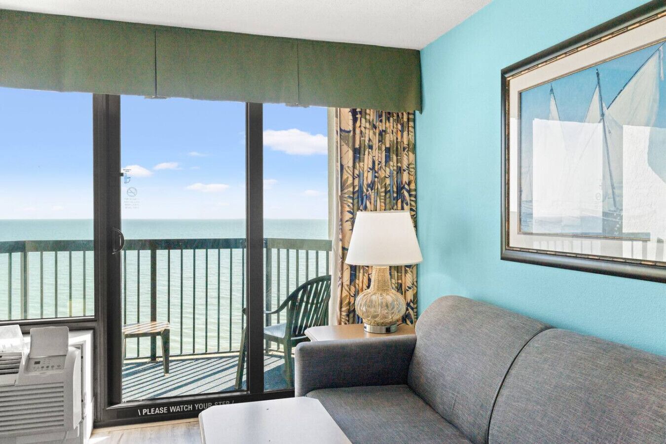 Un balcon avec vue sur la mer, un canapé, un fauteuil et une lampe.