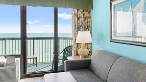 A balcony with a view of the sea, a sofa, a chair, and a lamp. - Beachfront End Unit Condo with Pools and Hot tubs (Myrtle Beach)