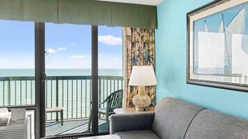 Un balcon avec vue sur la mer, un canapé, un fauteuil et une lampe.