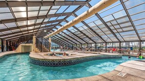 An indoor swimming pool with a glass ceiling, a hot tub, and lounge chairs. - Beachfront End Unit Condo with Pools and Hot tubs (Myrtle Beach)