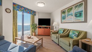 Ein Wohnzimmer mit großem Fenster, Flachbildfernseher, Sofa und Couchtisch.