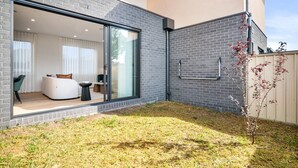 A modern house with a large sliding glass door leading to a living area with a white sofa and a coffee table. - Brand-new 3-bed Townhouse in Pascoe Vale (Melbourne)