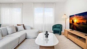 A modern living room with a sectional sofa, a coffee table, a TV, and a lamp. - Brand-new 3-bed Townhouse in Pascoe Vale (Melbourne)