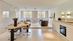 A modern kitchen with a dining area, a sofa, and a fireplace. - Sublim Apartment on Avenue Montaigne/eiffel Tower (Paris)