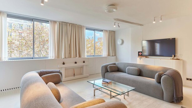 A modern living room with a sofa, a glass coffee table, and a flat-screen TV mounted on the wall. - Sublim Apartment on Avenue Montaigne/eiffel Tower (Paris)