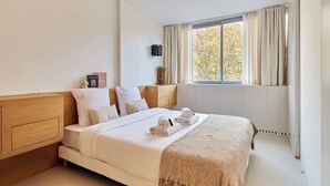 A hotel room with a large bed, a wooden headboard, a bedside table, a TV mounted on the wall, and a window with curtains. - Sublim Apartment on Avenue Montaigne/eiffel Tower (Paris)