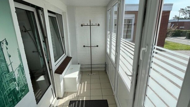 A narrow corridor with white walls, a black mat, and a coat rack. - Bungalow in Strandnaehe, Dornumersiel (Dornum)
