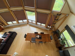 A spacious room with a high ceiling, large windows, a wooden dining table with chairs, a sofa, and a potted plant. - LUXURY SKI OR GOLF HOME 
4 Bedroom, 3.5 Bathroom 
Walk to Rusutsu Resort, Japan (Rusutsu, Abuta-Gun)