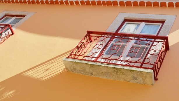 A balcony with red metal railings and a concrete ledge. - Stay by Sao Jorge Castle (Lisbon)