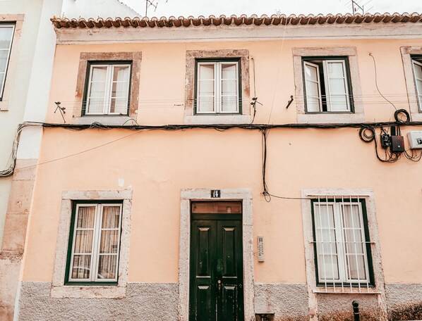 Un edificio con tres ventanas, una puerta y cableado eléctrico visible.