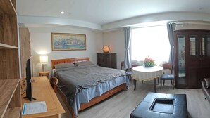 Ein Hotelzimmer mit Bett, Sofa, Schreibtisch mit Computer, Esstisch und Blick ins Freie.