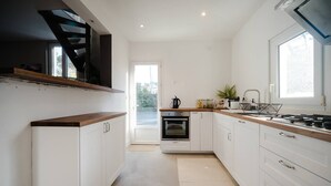 Une cuisine moderne avec des meubles blancs, un plan de travail en bois et un four encastré.