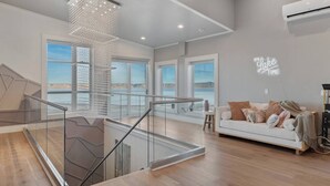 A spacious living area with a staircase, large windows, and a view of the outdoors.
