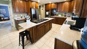 A modern kitchen with wooden cabinets, a central island, a stove, and a sink. - Skytop - Hands down the best view on Beaver Lake (Rogers)
