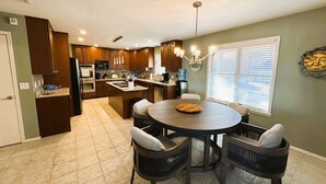 A modern kitchen with dark wooden cabinets, a central island, and a dining area with wicker chairs. - Skytop - Hands down the best view on Beaver Lake (Rogers)