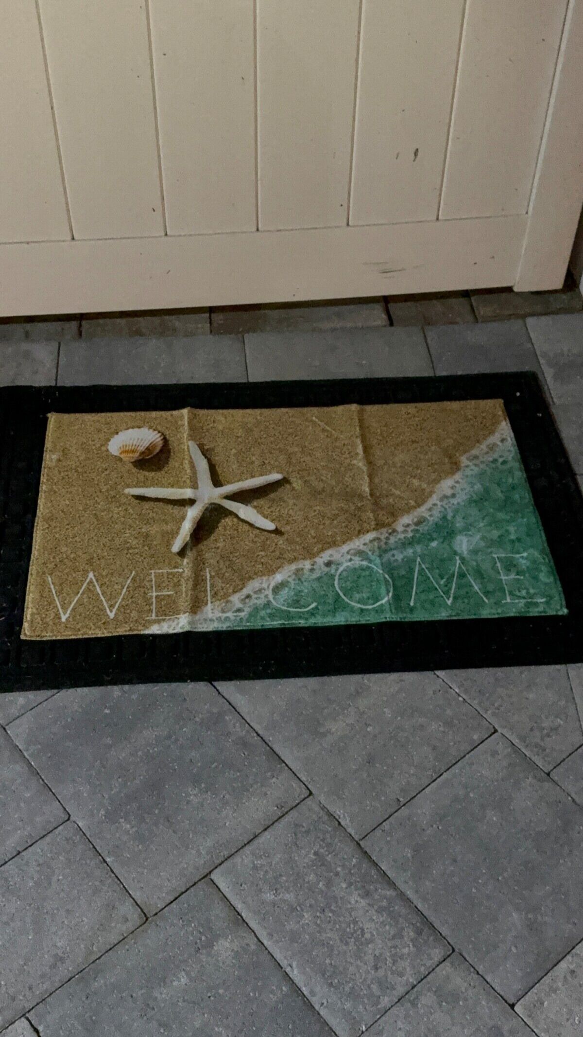 Eine Fußmatte mit Strandmotiv, inklusive Seestern und Muschel.