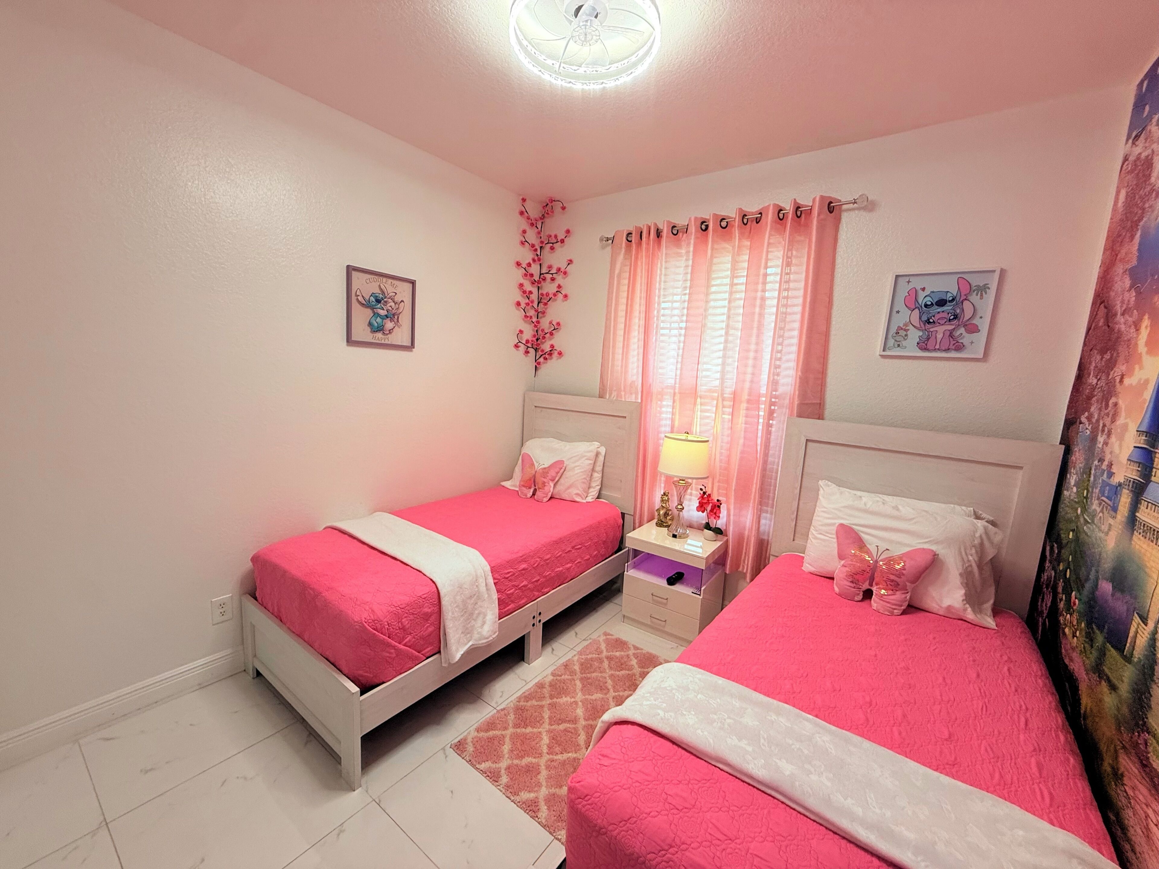 A bedroom with two beds, a nightstand, a lamp, and a wall with a picture.