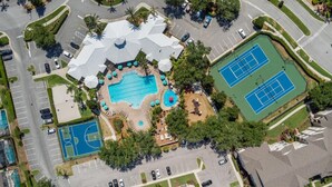 Oversigtsbillede af et resort med swimmingpool, tennisbaner og parkeringsplads.