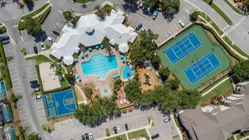 Vista aérea de un resort con piscina, canchas de tenis y estacionamiento.