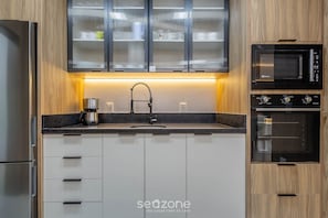 A modern kitchen with a stainless steel refrigerator, a coffee maker, a sink with a faucet, a microwave, and an oven. - Apt With 3 Suites, Barbecue and sea View Den1301 (Itapema)