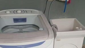 En tvättmaskin med frontmatning och en vit plasttvättkorg.