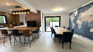 Una cuina moderna amb una illa gran, zona de menjador amb cadires i un mapa del món a la paret.