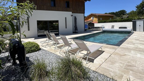 Un edifici modern amb piscina, mobiliari exterior i zona de jardí.