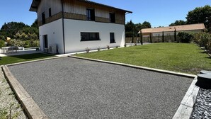Una casa moderna de dos pisos amb façana blanca, un carrer d'accés pavimentat i un jardí ben cuidat.