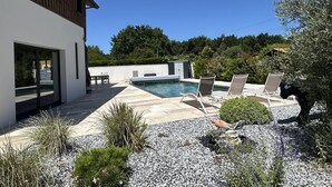 Una casa moderna amb piscina, zona d'estar a l'aire lliure i jardí.