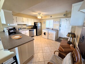 A compact kitchen with a microwave, refrigerator, dishwasher, and a washing machine. - Beachfront Gem w/ Extended Balcony & Tennis View (St. Augustine Beach)