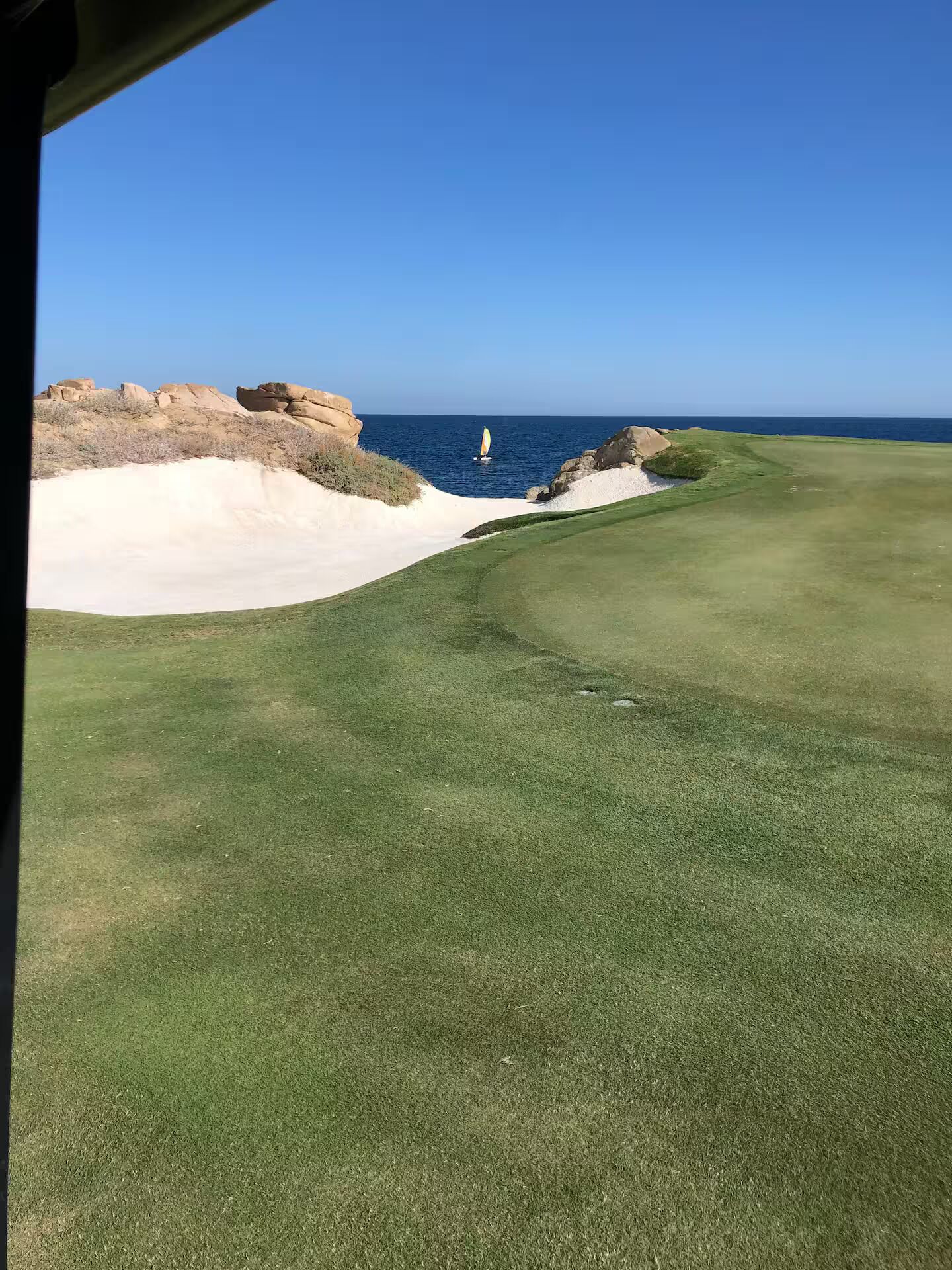 Ein Golfplatz mit freiem Blick auf das Meer und steilen Felsen.