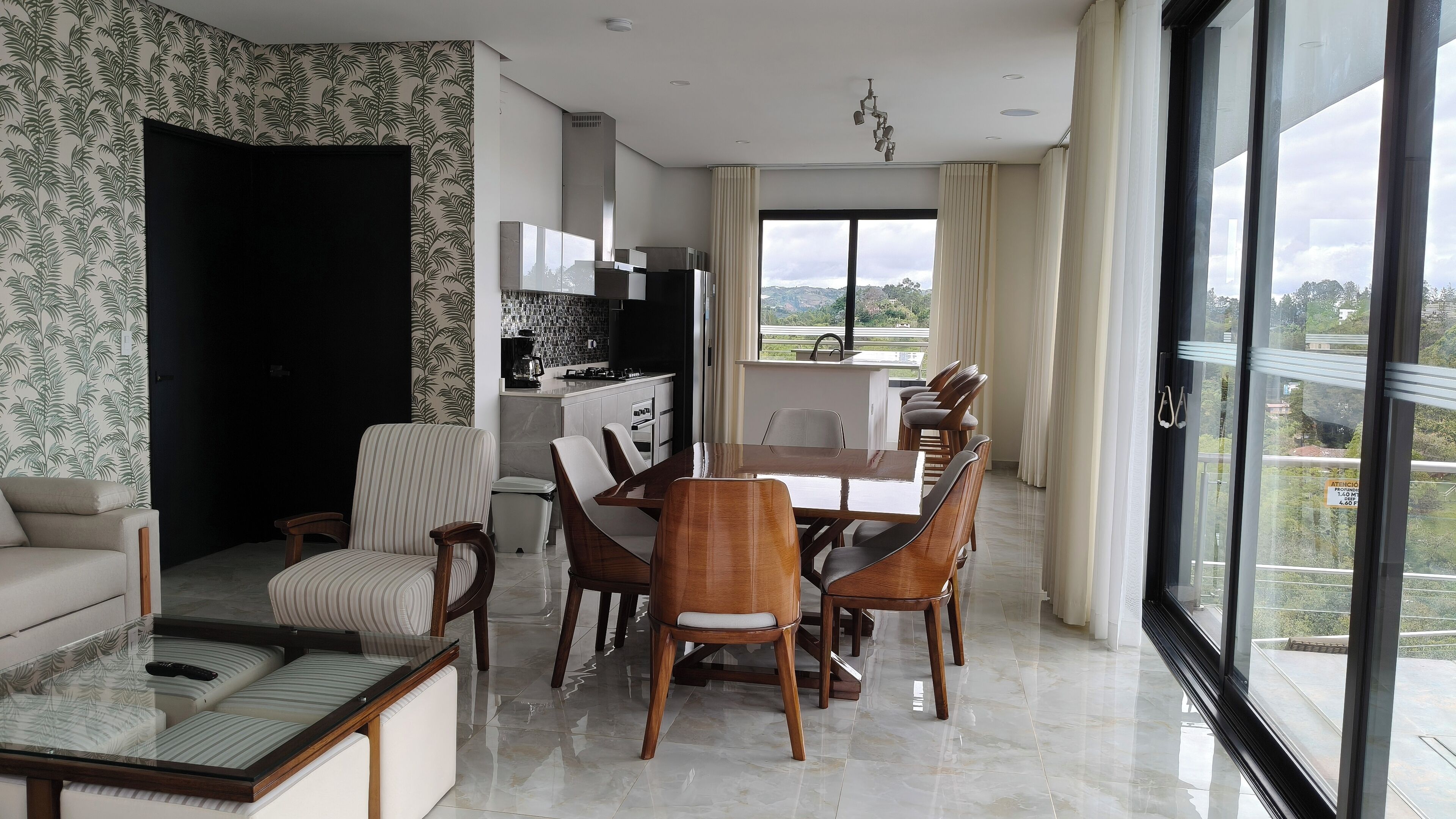 Una sala de estar moderna con comedor, ventanas amplias y cocina.