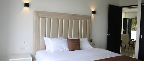 A neatly made bed with a wooden headboard, white bedding, and two wall-mounted light fixtures.