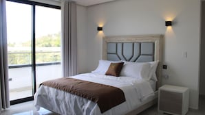 Habitación de hotel moderna con una cama grande, una mesita de noche y vistas a través de un ventanal corredero.