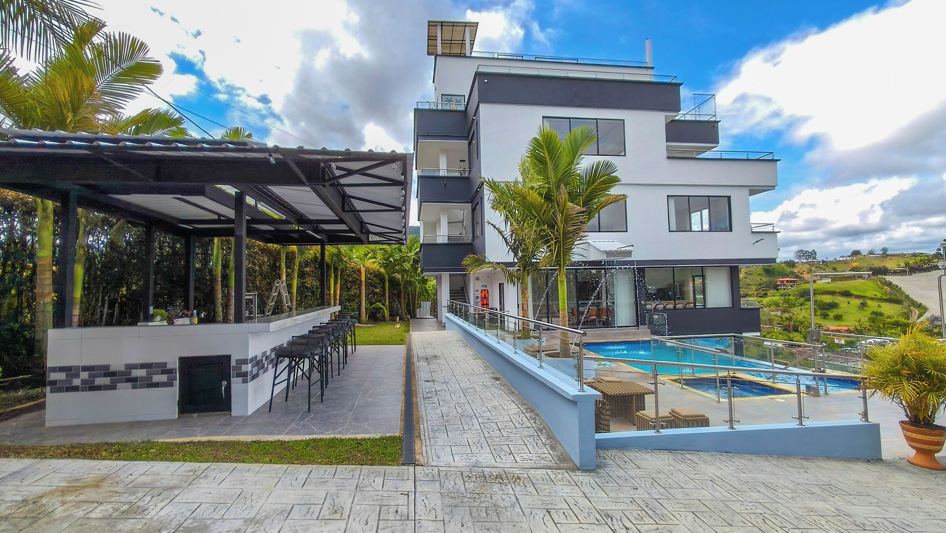A modern building with a pool, outdoor seating, and a covered patio area.