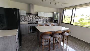 A modern kitchen with a white countertop, a built-in stove, and a large window offering a view of greenery.