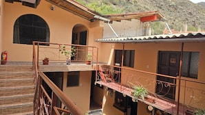 A multi-level building with balconies, potted plants, and a fire extinguisher. - REFUGIO SAGRADO BOUTIQUE (Ollantaytambo)