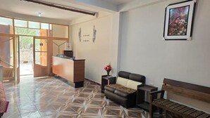 A reception area with a reception desk, a sofa, a bench, and a wall-mounted picture. - REFUGIO SAGRADO BOUTIQUE (Ollantaytambo)