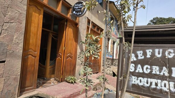 A building with a wooden door and a sign that reads "Refugio Sagrado Boutique." - REFUGIO SAGRADO BOUTIQUE (Ollantaytambo)