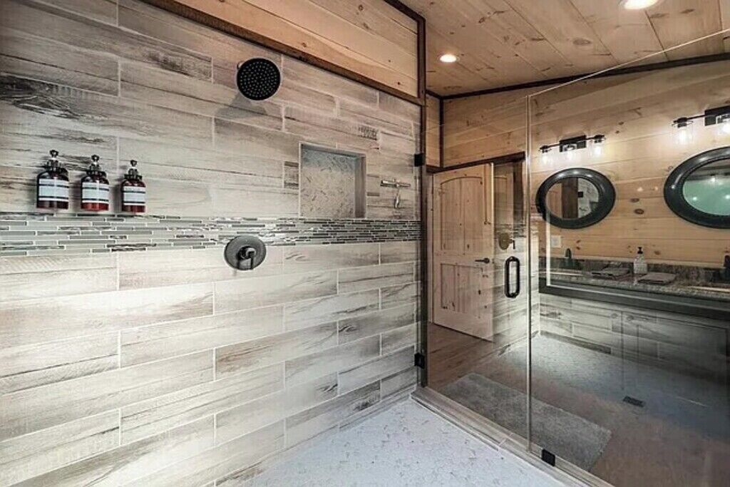 Une salle de bain moderne avec un mur en bois, une cabine de douche en verre et un miroir.
