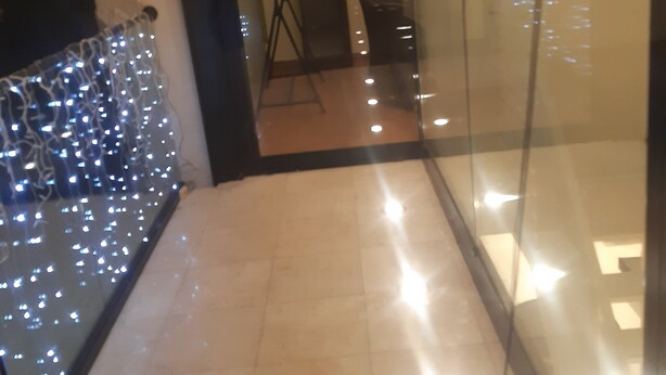 Un pasillo con una pared de vidrio que refleja una habitación con una silla y una mesa.