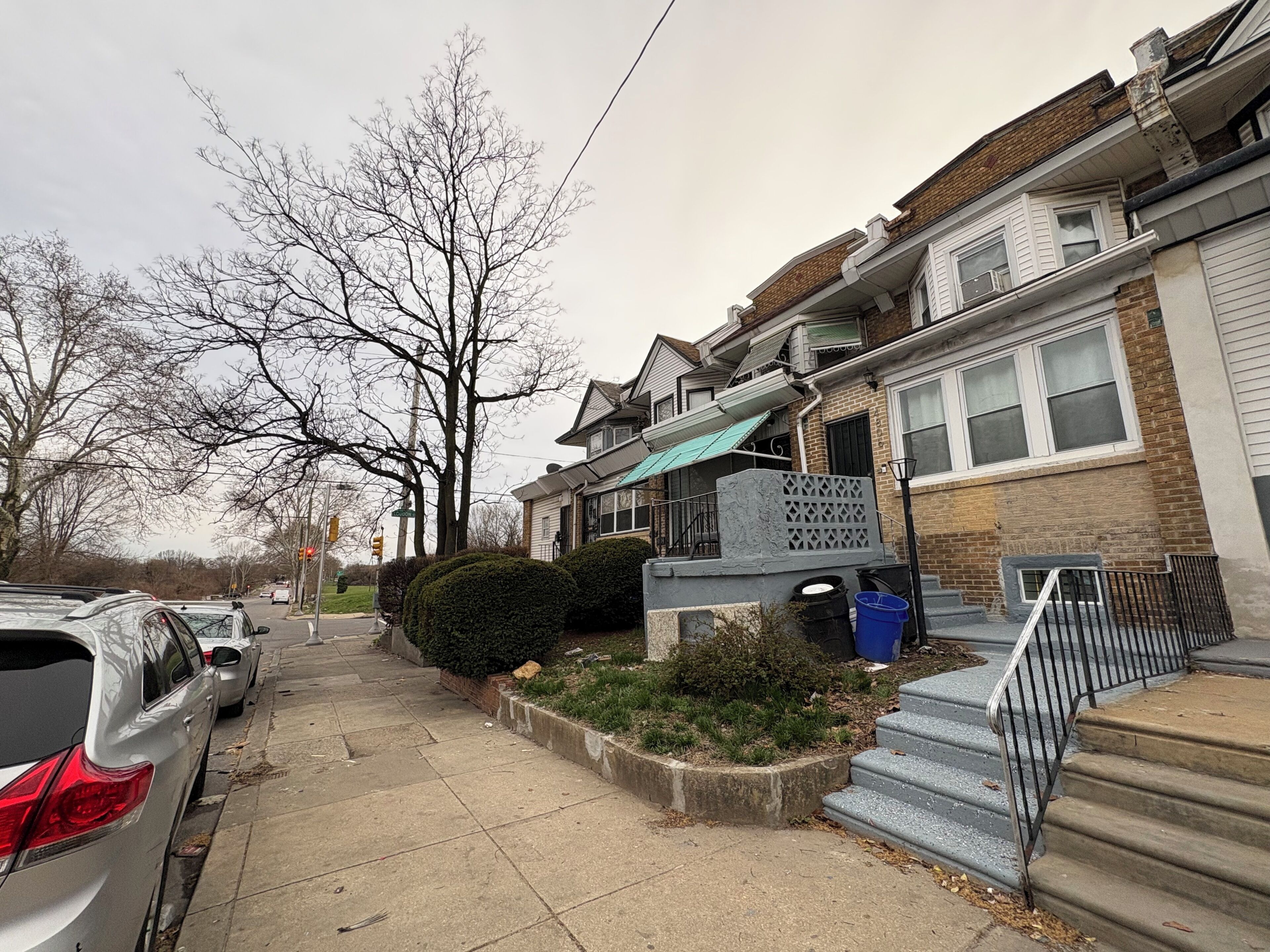 A residential street with houses, parked cars, and a sidewalk.