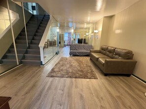 Un salon moderne avec un escalier, un canapé à motifs, un divan en cuir et un plancher en bois.